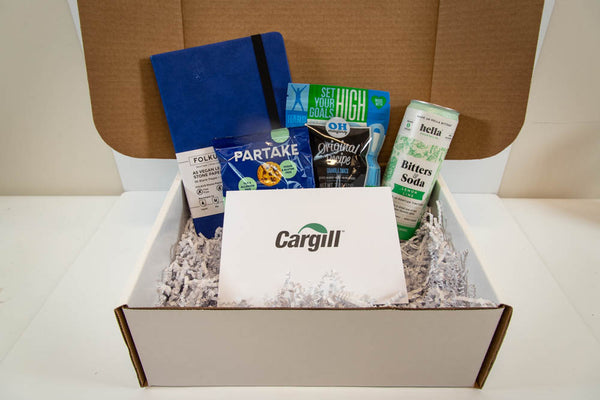 photo of gift box with notebook, cookies, granola, bitters and soda and notecard with Cargill logo printed on it