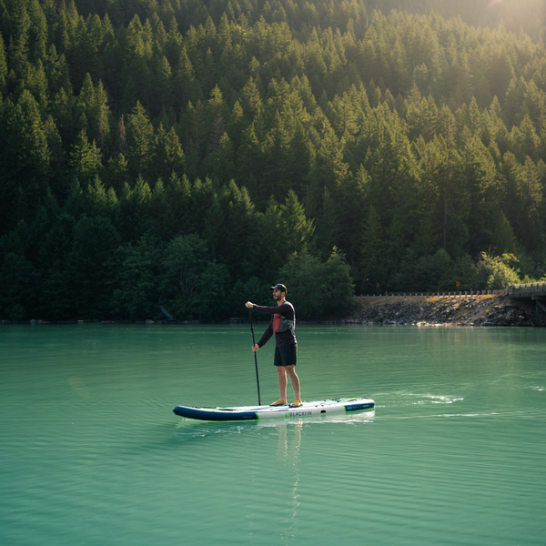 Person paddling on the BLACKFIN standup paddle board on rocky shoreline