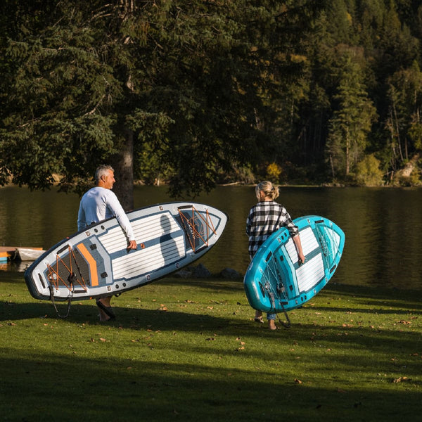 Woman and man carrying BLACKFIN standup paddle board to the water