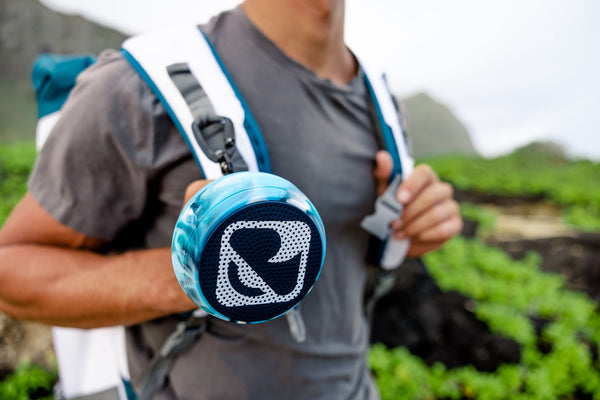 Man hiking with speaker on his backpack.