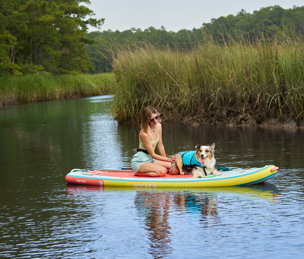Woman paddling on a iROCKER standup paddle board with her dog