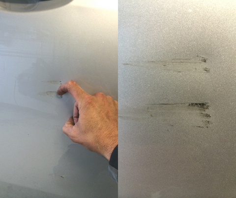 someone demonstrating the fingernail test on a car with paint damage
