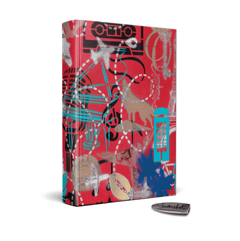 On a white background, a hardback deluxe edition of Bernie Taupin's Scattershot stands upright. It's red clothbound cover is designed by Bernie and features illustrative motifs including planes, cassette tapes and treble clefs, phone boxes in bold blues, greens, golds and black. Next to it lies a silver USB stick, with Scattershot etched in cursive on one side.