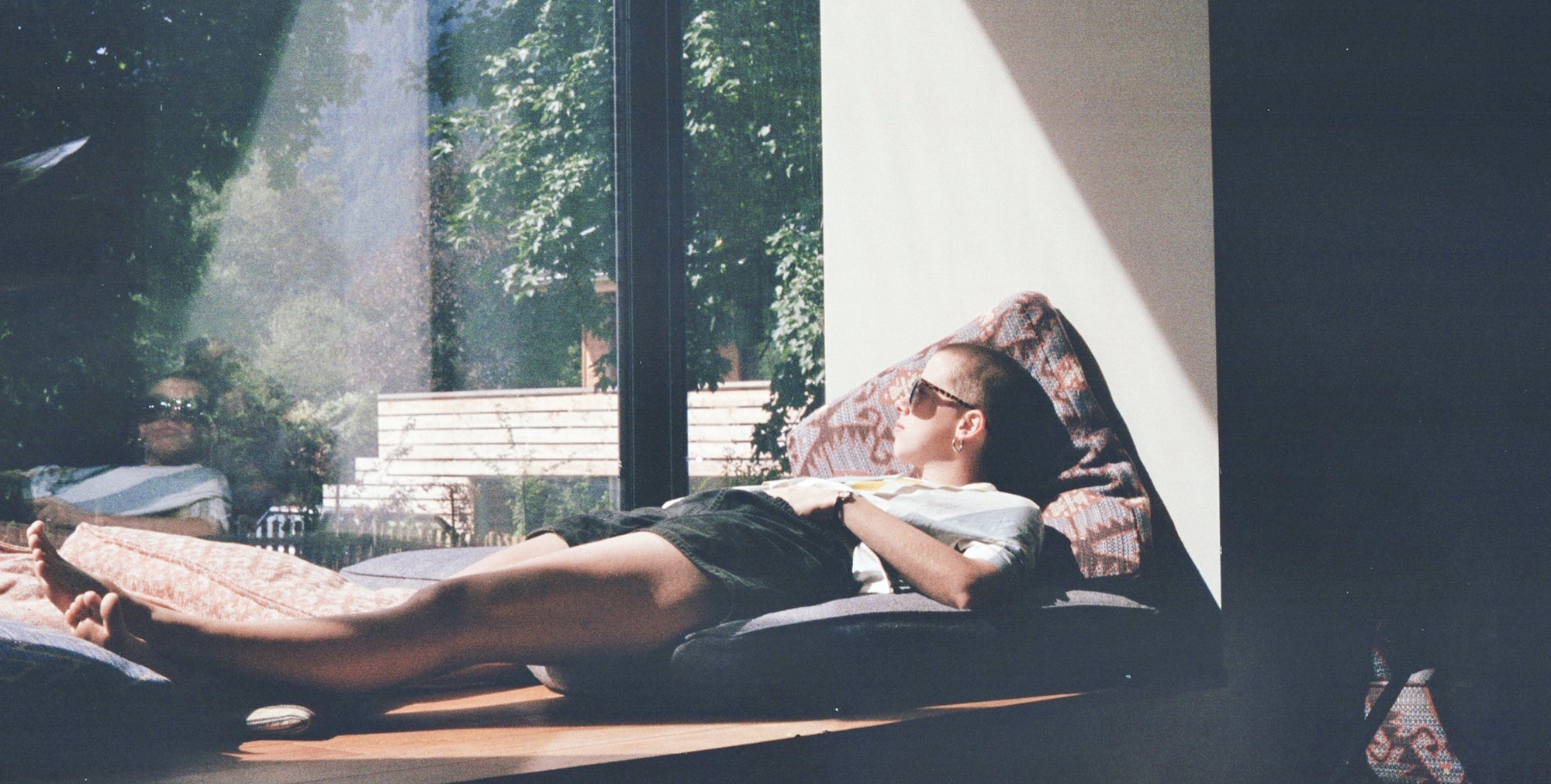 young male enjoying cbd cigarette relaxing by the window