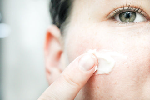 woman applying royal jelly, green tea, and vitamin b3 face cream