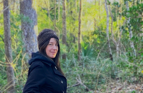Shay in coat and hat walking in the woods