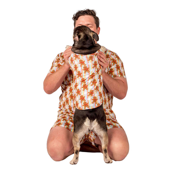 A human and French Bulldog wearing Christmas printed pajamas.