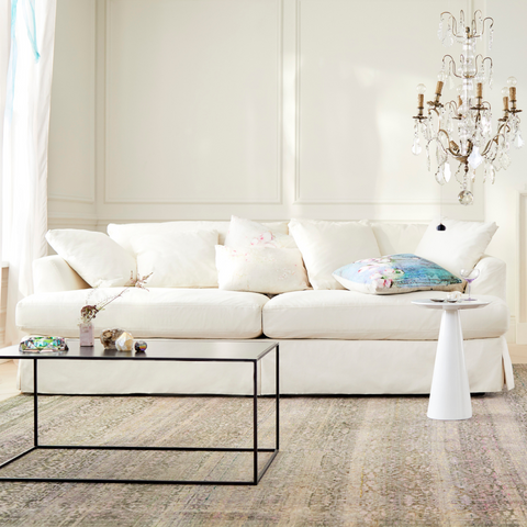 White Cotton Sofa in living room with rug, coffee table, and chandelier 