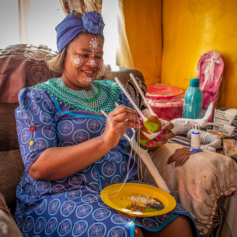 Woman beading in her home