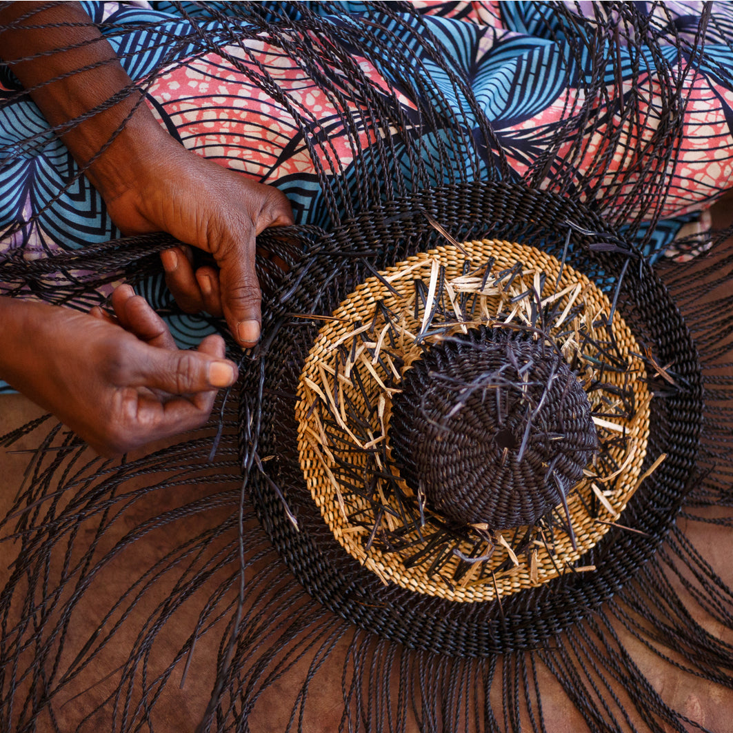 Close up of an artisan weaving a basket by hand