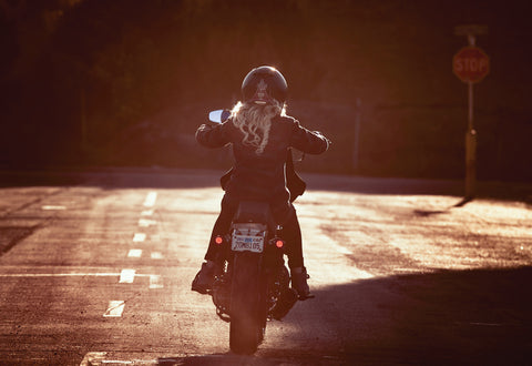 Female motorcyclist riding into distance wearing a cruiser style motorcycle jacket