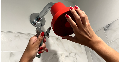 two hands installing a red showerhead with a wrench, how to filter chlorine from shower water