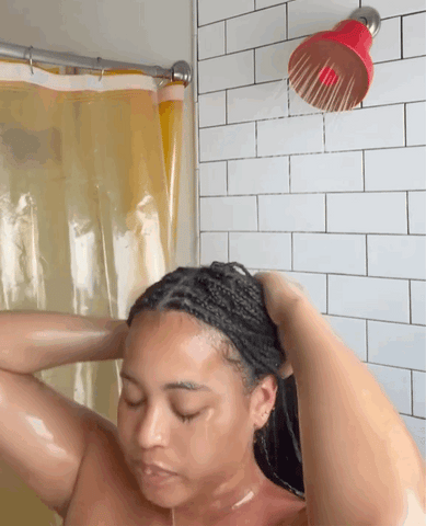 woman with dark braided hair showering with a red Jolie filtered showerhead