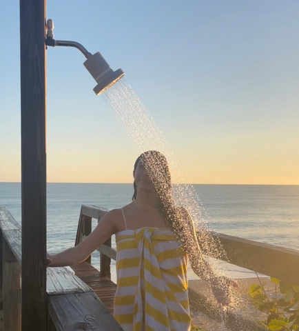 woman in towel using outdoor shower at beach, best shower heads with filter