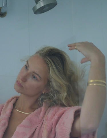 blonde woman in pink robe fixing hair, hair loss in shower