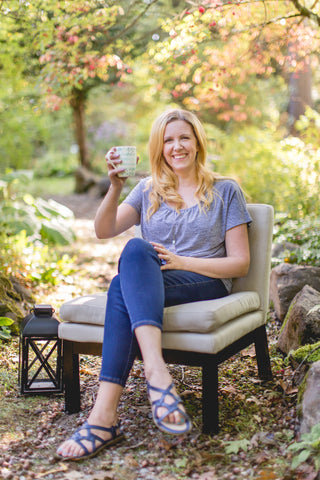 smiling woman holding cup of tea sitting in a garden