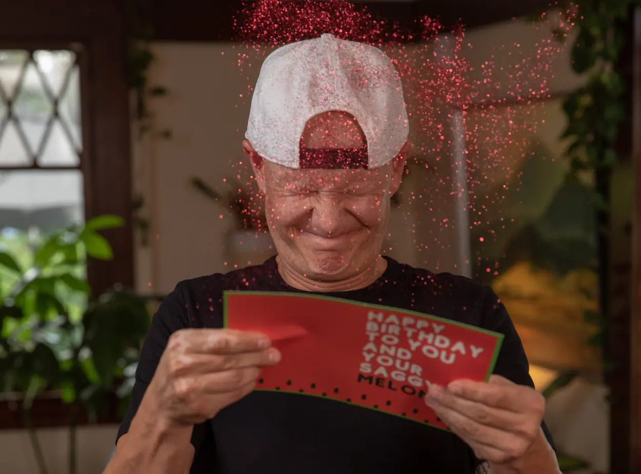 Guy opening glitter bomb card all over face