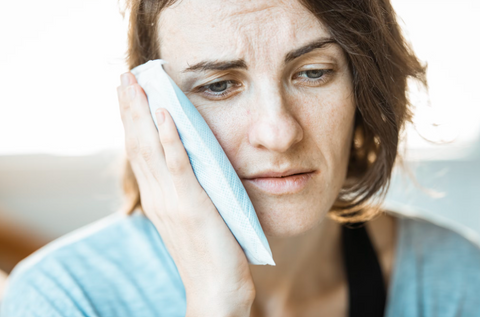 Woman using a cold compress to alleviate jaw pain.
