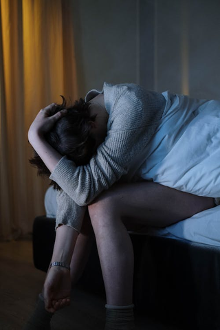 A person sitting on a bed looking tired