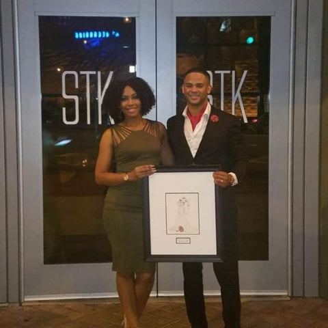 couple holding a sketch of their dress and suit.