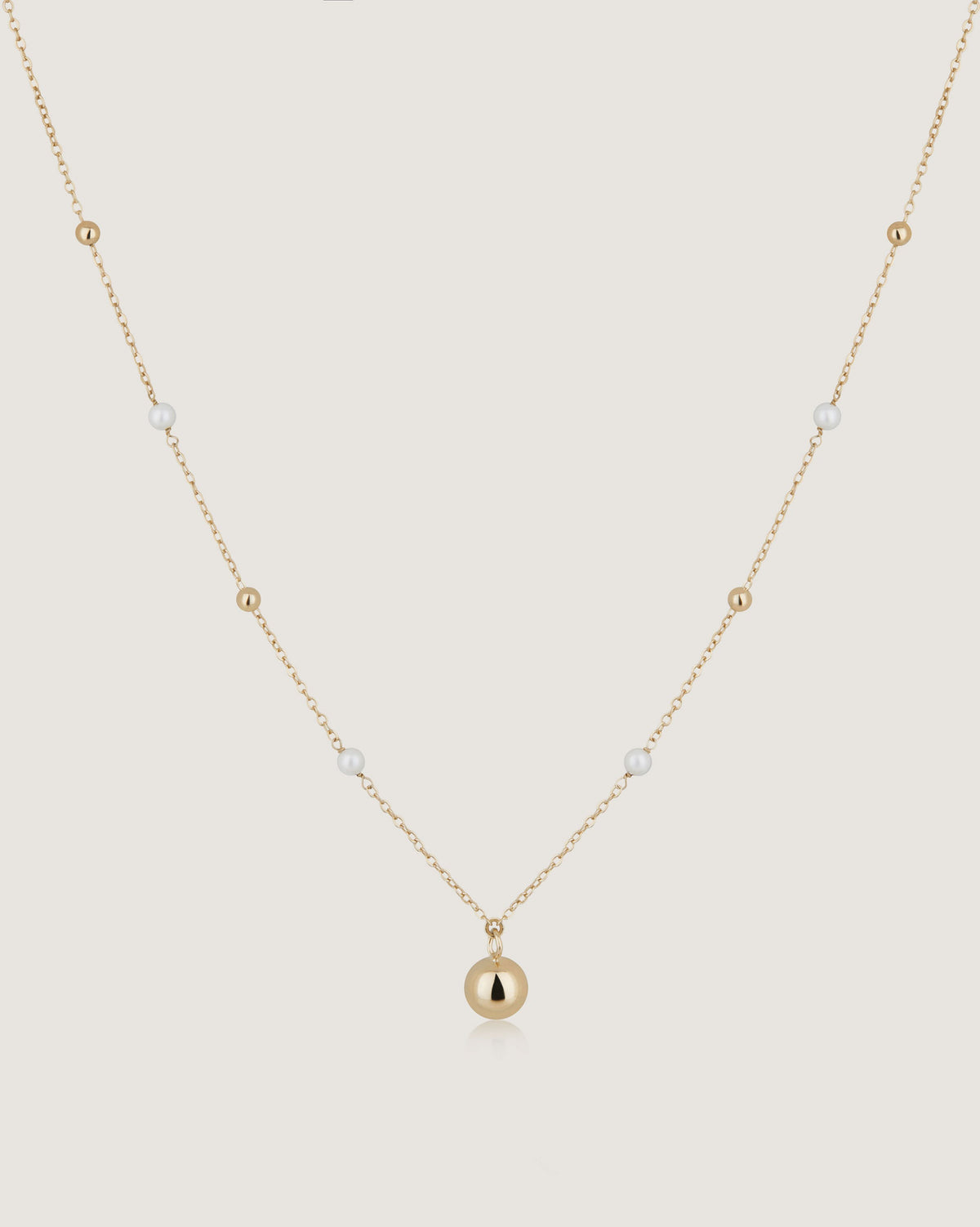 A gold necklace with a ball on it