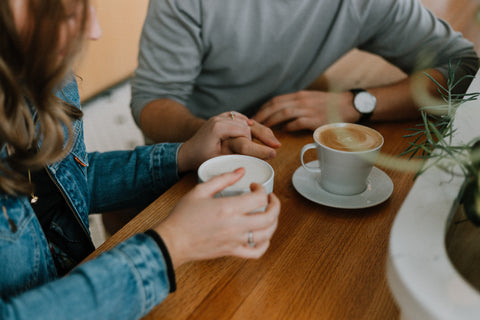 Koppel die handen vast houdt en koffie drinkt