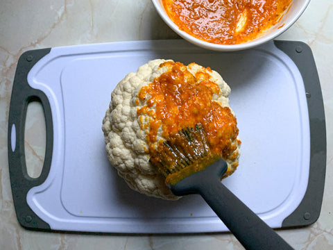 cauliflower being brushed with an amber sauce 