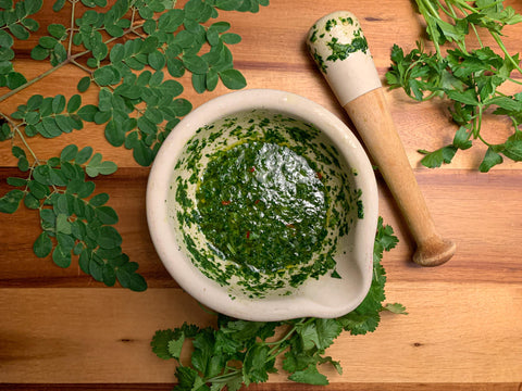 chimichurri in a mortar with a pestle on the table beside
