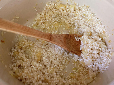 unprepared risotto in a bowl with a wooden spoon