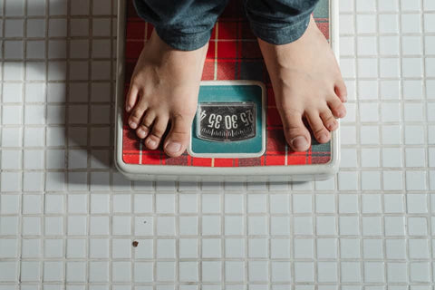 a boy standing on weighing scale( Nagarmotha helps in managing weight)