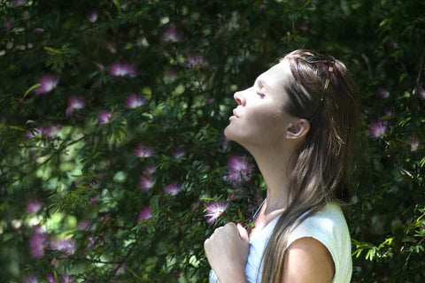 Bringraj powder for treating Asthma ( Image - A woman in a garden breathing deeply with closed eyes)