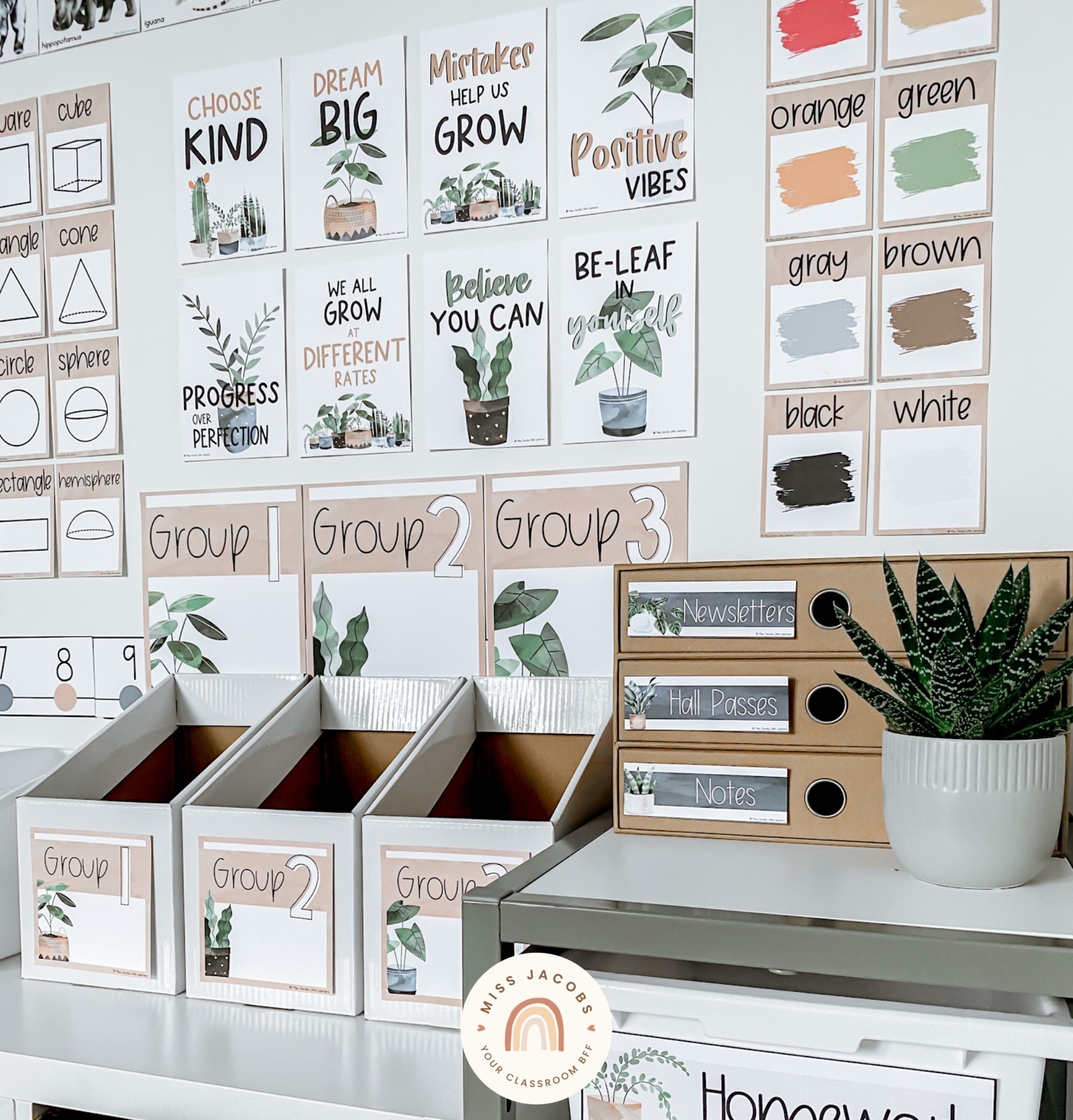 Two images show a wide range of the new Boho Plants decor products. The left images shows a shelving unit with magazine boxes on top and a small set of mini drawers colloquially called a ‘teachers toolbox.’ Then to the side is a taller series of draws on a trolley. The wall shows alphabet posters and a number of calendar displays. The tones are all earthy with nudes, white, greens, blues and pops of orange. The right image is a closer angle and shows a series of motivational posters, and posters showing different colours.