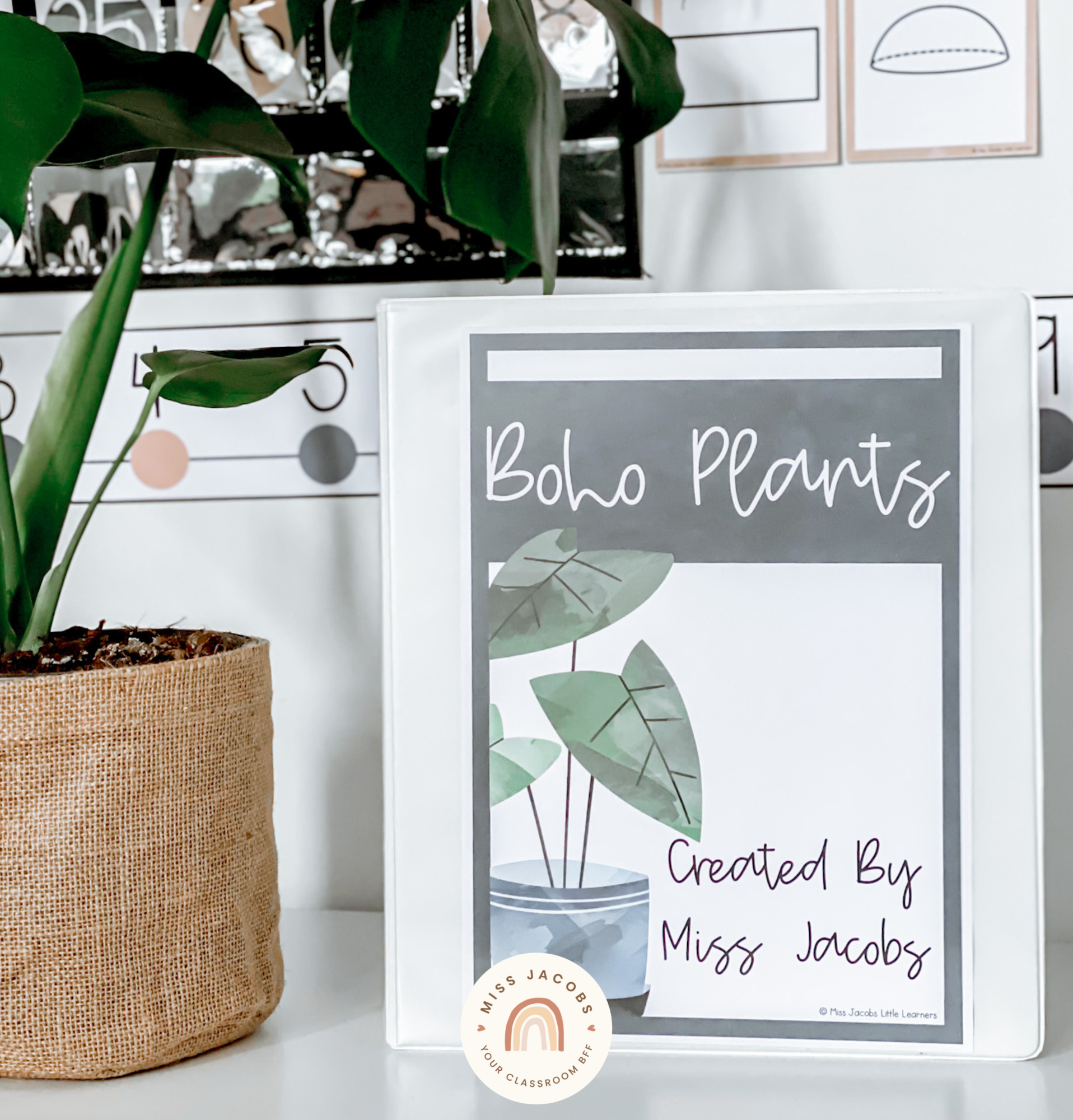 There are two images. In the first we see the top corner of a bookshelf, and inside are a series of the white binder with the Boho Plants labels. There’s an illustration of a plant on the base and handwriting font spelling out the months of the year. Next to the shelf is a trolley with drawers that also contain the Boho Plants labels. There are large plant illustrations that span across a number of the labels, which also feature the days of the week in cursive font. The right-hand image shows a closeup of a binder cover, it says ‘boho plants’ and features an illustrated pot plant with a blue pot and big dark green leaves. The heading is white handwriting font against a black background.
