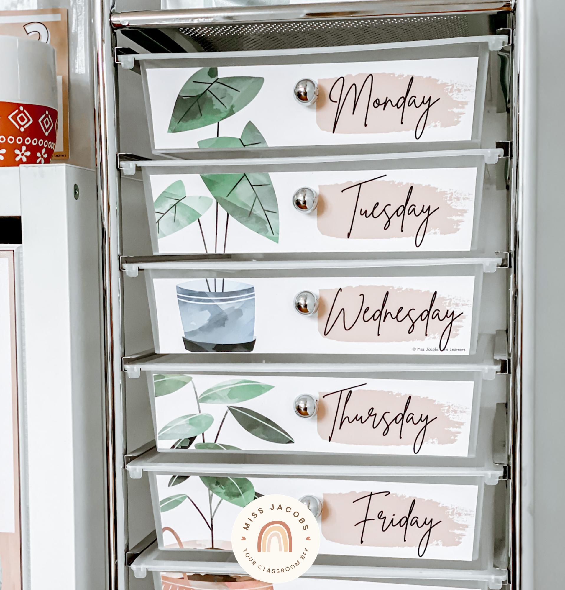 There are two images. On the left is what’s often called a teachers’ toolbox, which is a cube of mini shelves. The shelves are labelled with items from the Boho Plants range. The labels feature a nude coloured base that looks like a paint swipe, with black capital lettering. The draws are labelled with items like ‘notes’ ‘pins’ ‘tape’ and ‘clips’.