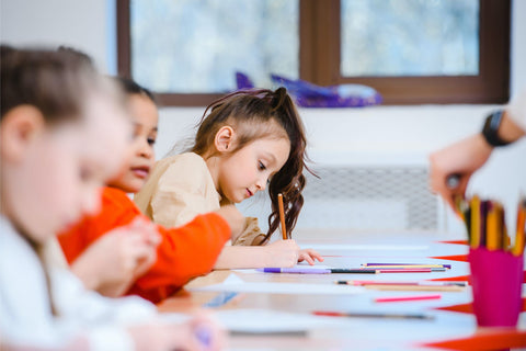 Very young students independently working with pencils and coloured textas