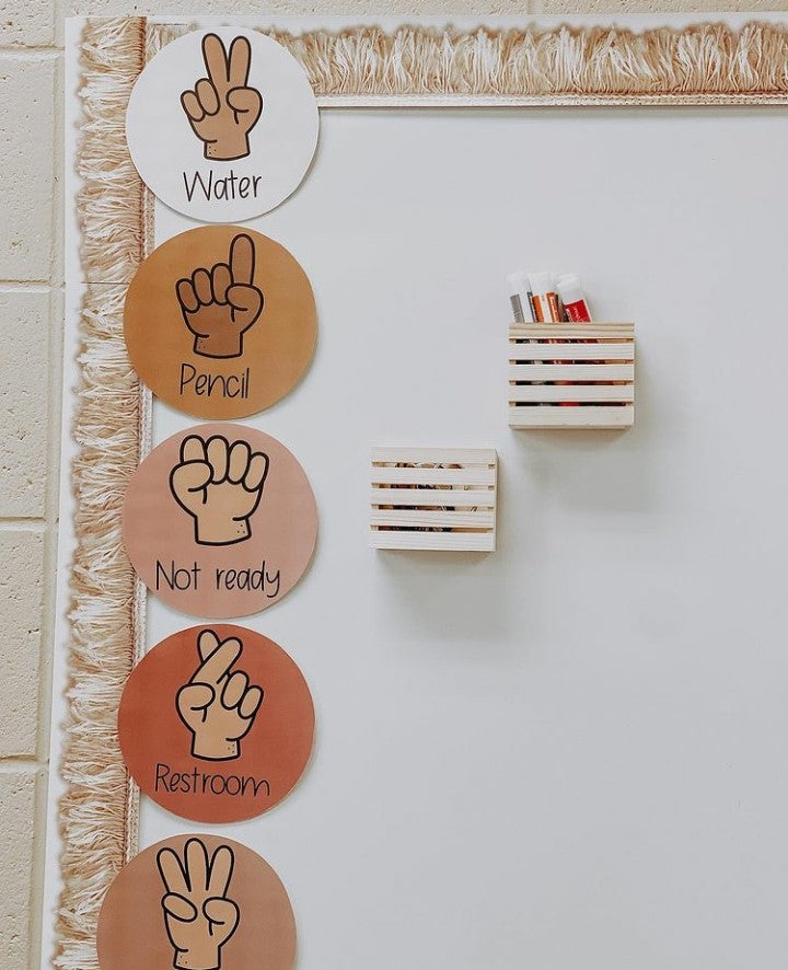 Two images show classroom displays with neutral tones. On the right we see a number of displays including Voice Levels, Alphabet posters and a calendar. On the right it’s a close up with hand signals indicating water, pencil, not ready and restroom.