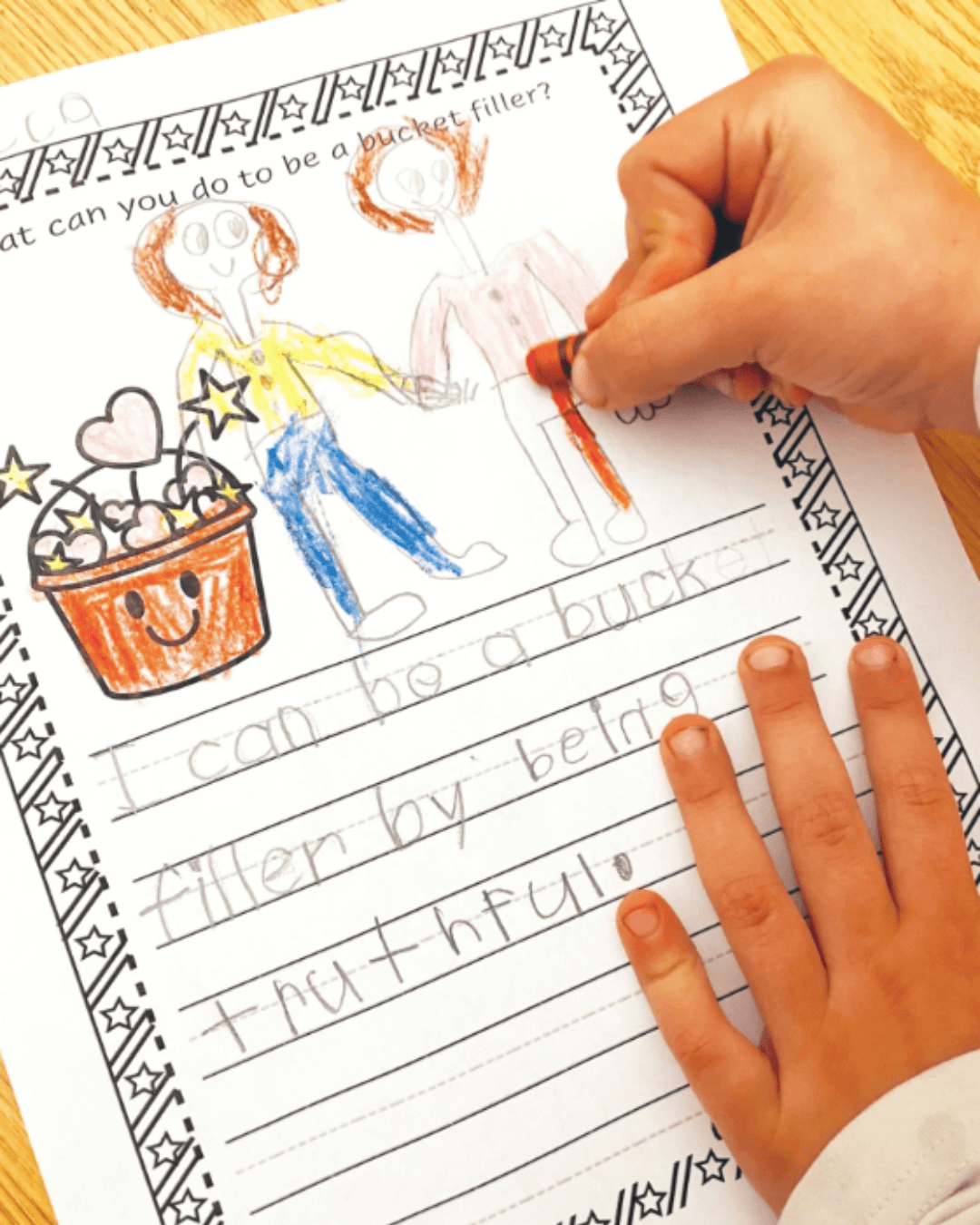 In the left image Sabrinna holds a child’s drawing of a bucket with pom-poms, the right image shows a worksheet with the words ‘I can be a bucket filler by being truthful.’