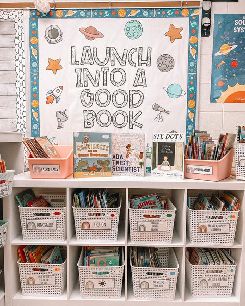An incredible classroom library set up by my BFF Lauren, featuring shelves organised with book storage baskets and a space-themed bulletin board that reads “Launch into a good book.”