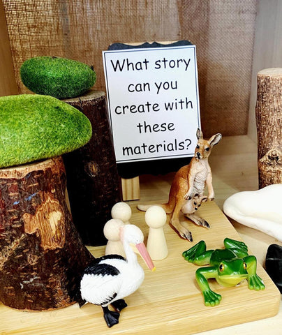 Two images show a selection of nature-themed items. In the left hand image, a prompt can be seen that says ‘What story can you create with these materials?’ Items include a mini frog, pelican, a tiny wooden house and a felt tree.