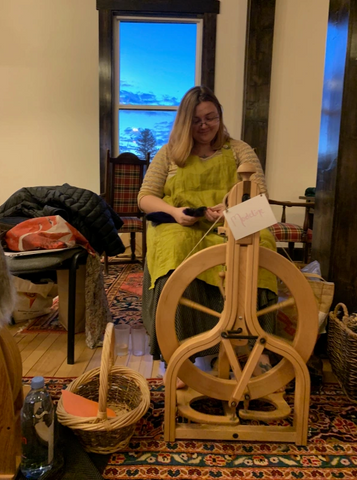 Madeline sits at her wheel and spins at Yarn & Yoga 2017