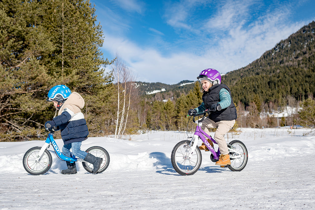 Zwei Kinder fahren auf Boom Kinderfahrrädern über einen Waldweg
