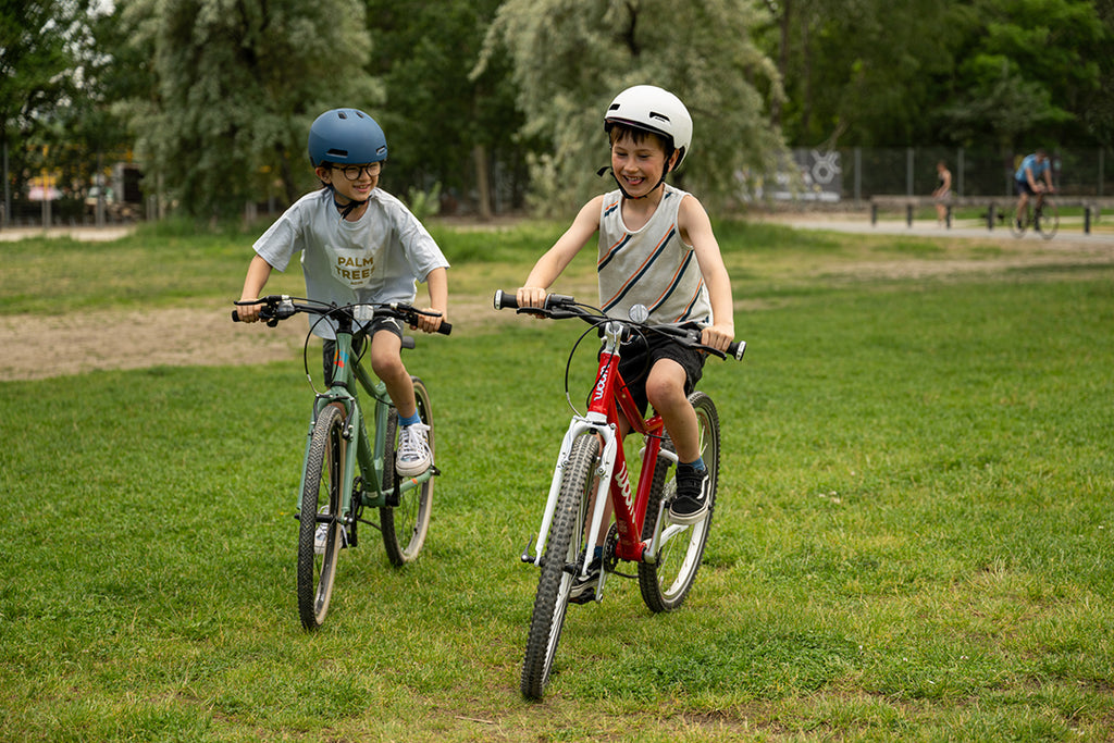 Zwei Jungs fahren mit ihren Kinderfahrrädern über eine Wiese
