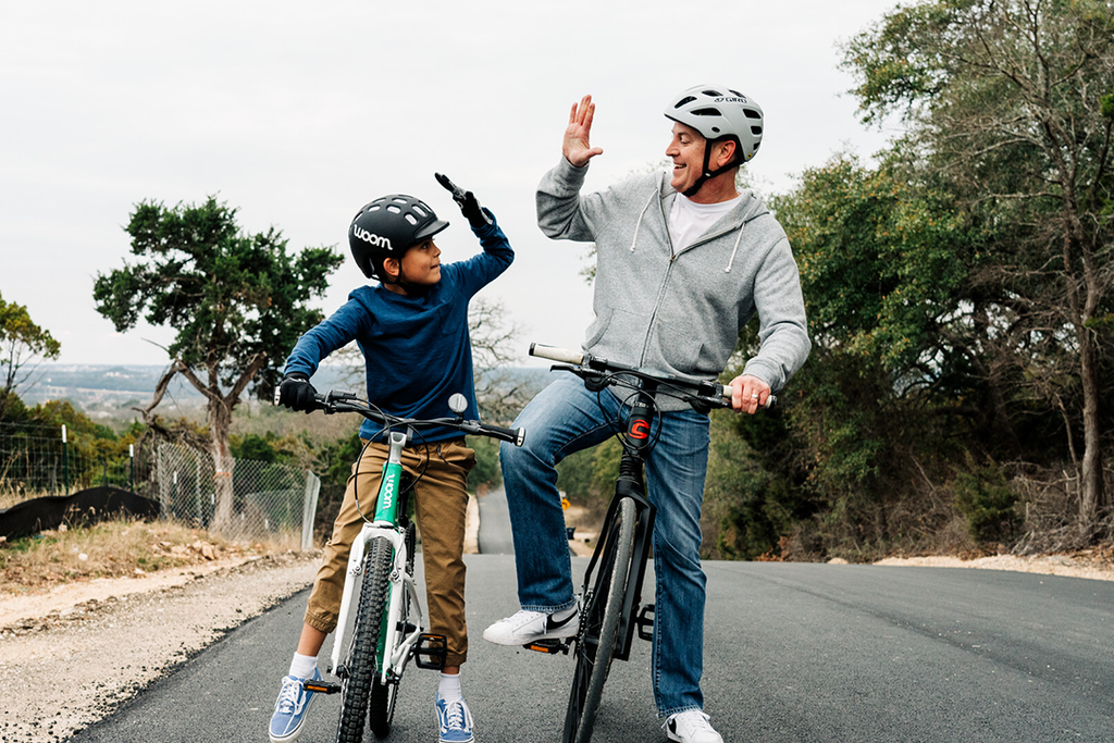 Mann und Junge stehen mit Fahrrädern auf der Straße und geben sich ein High Five