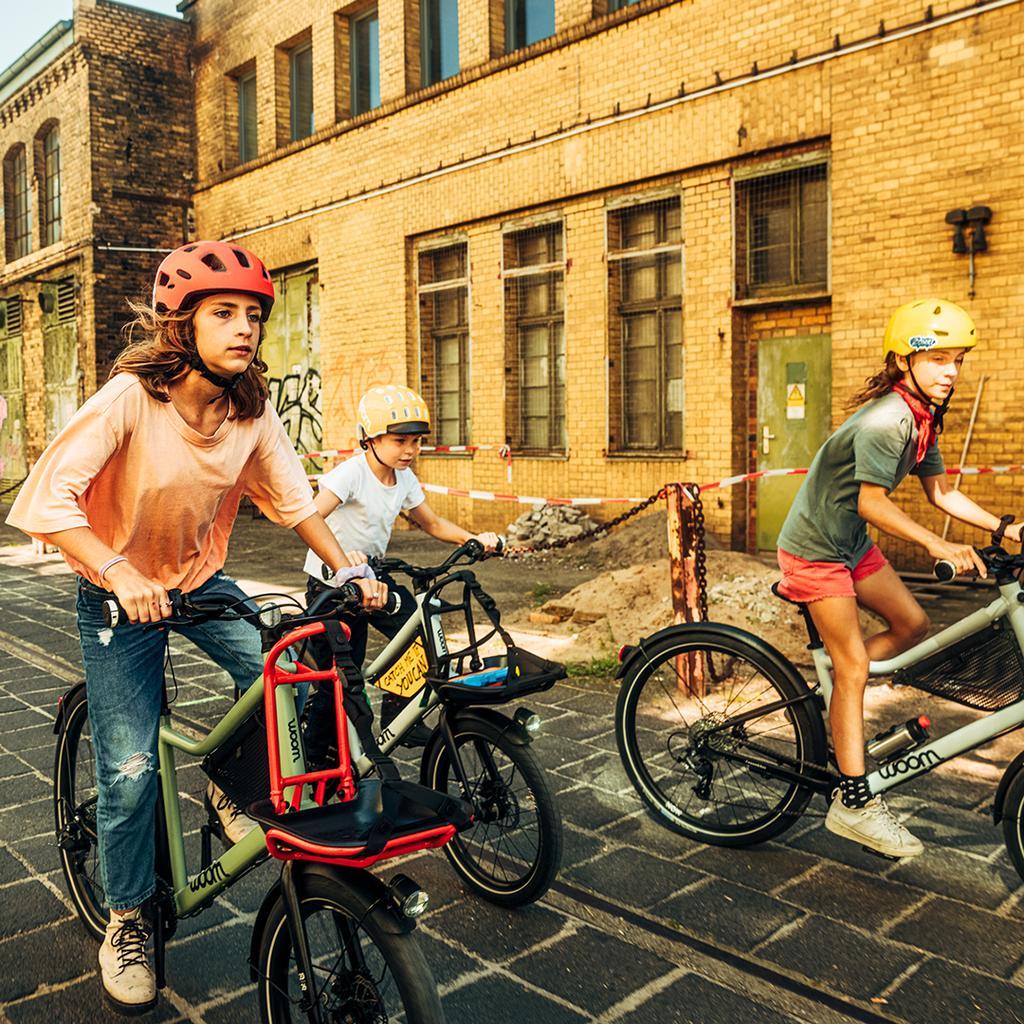 Drei Teenager fahren mit Woom NOW Kinderfahrrädern durch die Stadt