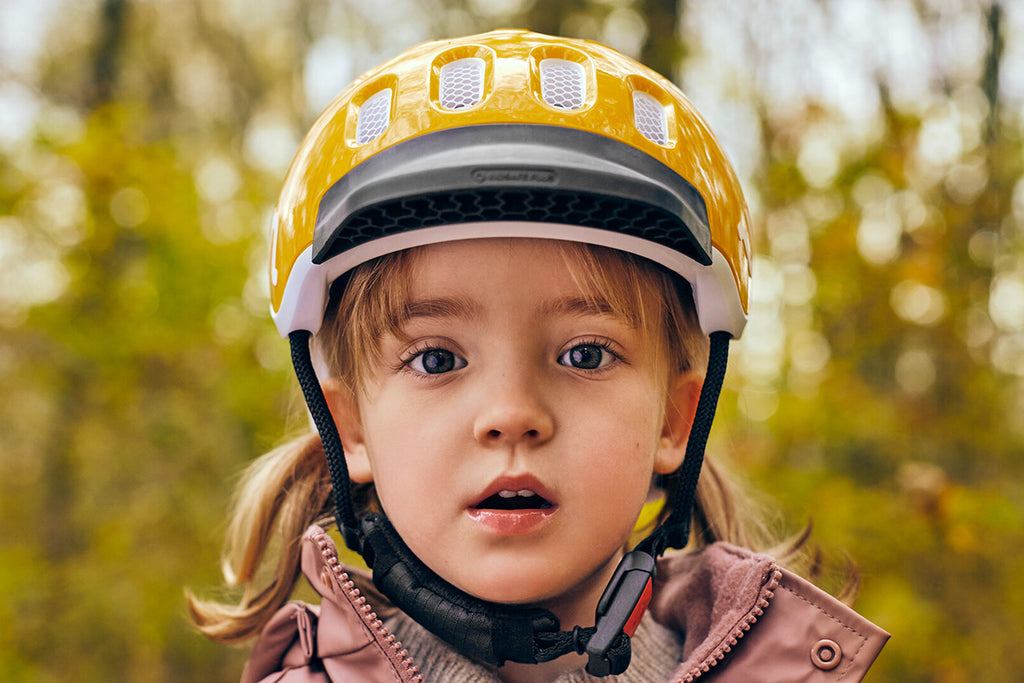 Kleines Mädchen trägt einen Fahrradhelm und schaut in die Kamera