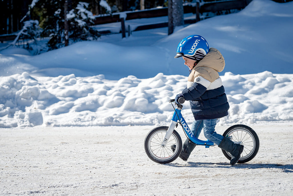 Kind fährt mit blauem Wood Laufrad durch den Schnee