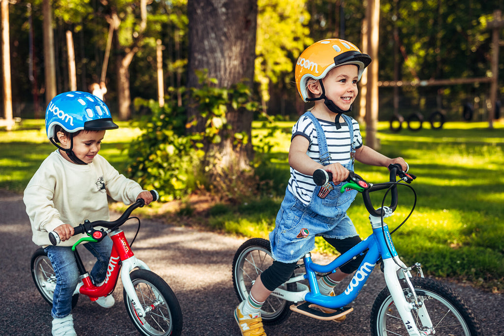 Zwei Kinder fahren auf Woom Laufrädern
