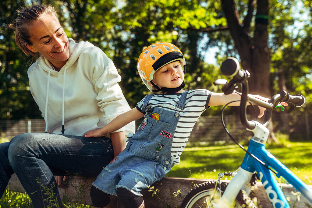 Frau sitzt mit kleinem Kind und Woom Kinderfahrrad