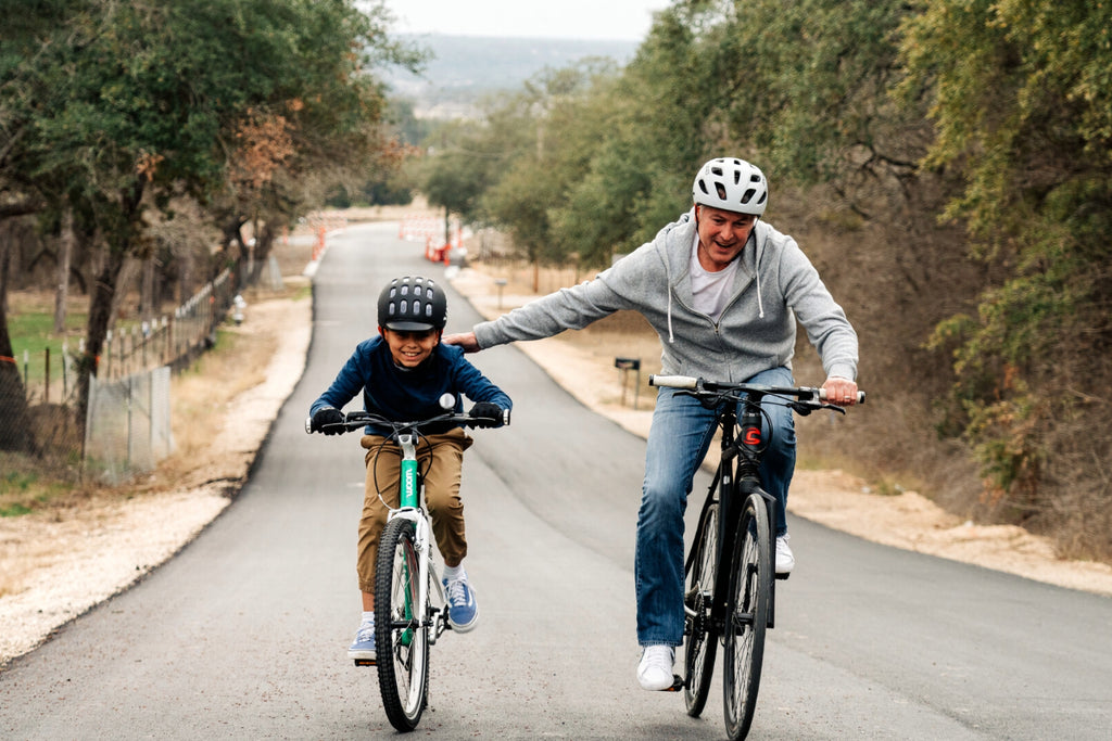 Junge und Mann fahren auf Fahrrädern einen Hügel hoch