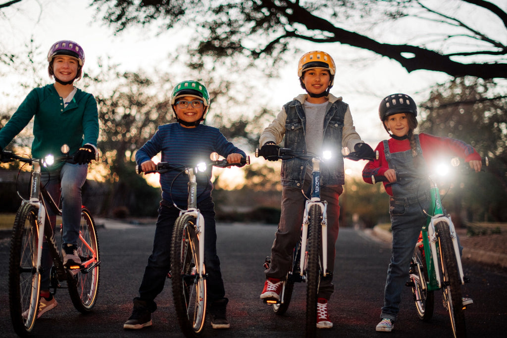 Vier Kinder stehen mit ihren Woom Kinderfahrrädern auf der Straße